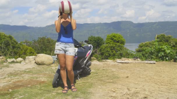 Una mujer se pone un casco y gafas de sol para un viaje en scooter — Vídeo de stock