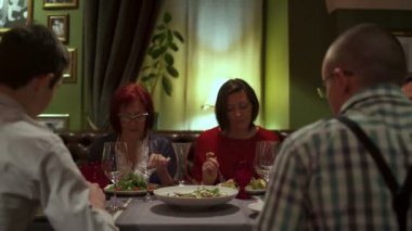 Restoranda bir masada oturan insanlar, yemek ve konuşmak