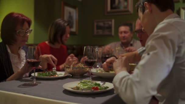 Gente en el restaurante, sentada en una mesa hablando y comiendo — Vídeos de Stock