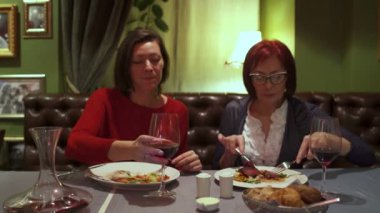 Restoranda bir masada oturan kadınlar ve salata ve sığır eti yemek biftek.