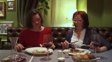 Restoranda bir masanın arkasında oturan kız gözlük tıklatması ve kırmızı şarap içmek