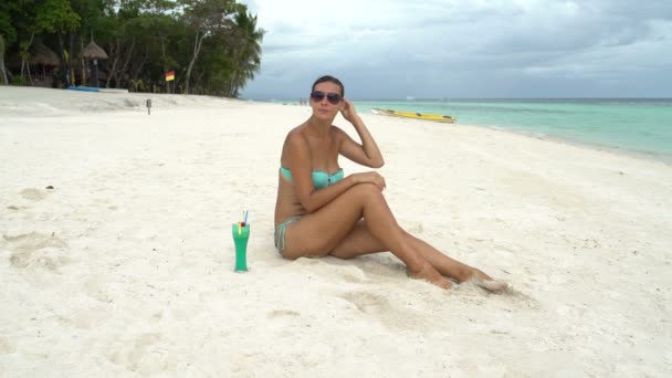 Женщина пьет коктейль, сидя у моря — стоковое видео