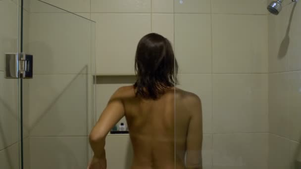 Женщина заходит в душ и умывается. — стоковое видео
