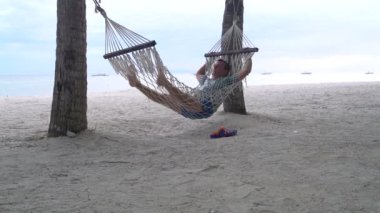 Deniz kıyısında bir hamakta sallanan bir adam