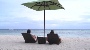 Bir adam bir tembel denizin kenarında yatan bir kadınla