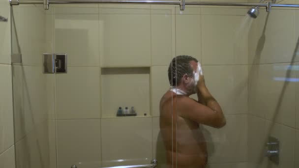 A man washes his head in the shower — Stockvideo