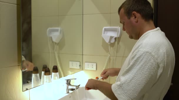Muž, čistit si zuby před zrcadlem — Stock video
