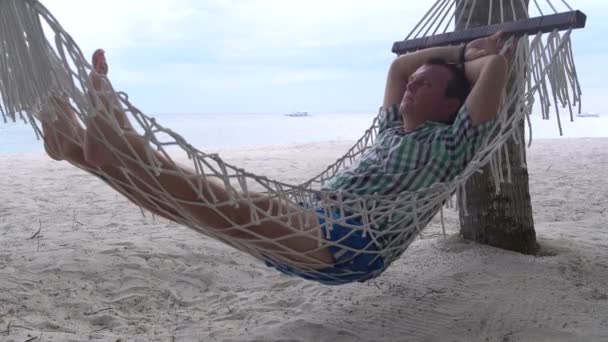 Egy férfi fekszik egy függőágyban, kilátással a tengerre — Stock videók