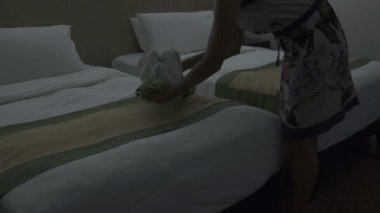 Hizmetçi bir otel odasında yatakta havlu tavşan koyar