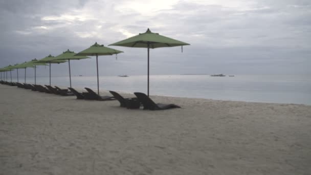 Camas de sol com guarda-sóis na costa do mar à noite — Vídeo de Stock