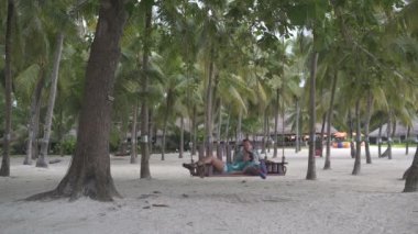 Avuç içi arasında bir salıncak üzerinde sallanan bir kadın ve bir erkek. Kadın alır ve gider