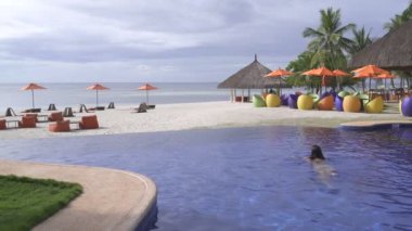 Kadın deniz manzaralı açık yüzme havuzunda yüzüyor