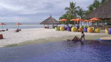 Bir kadın bir mayo deniz manzaralı açık yüzme havuzunun yanında yatıyor