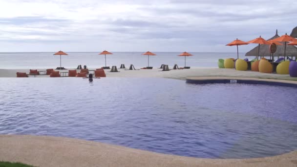 Un hombre se encuentra en la piscina al aire libre y con vistas al mar — Vídeo de stock