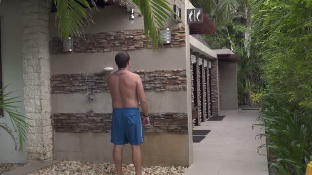 A man is washed in the shower outdoors — Stockvideo