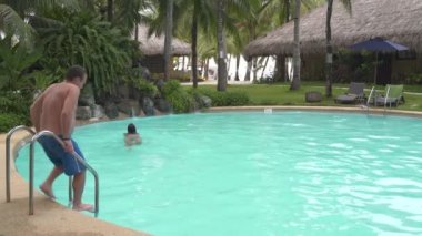 Bir kadın ve bir adam bir yapay şelale ile açık yüzme havuzunda yüzme