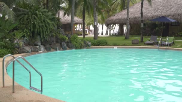 Eine Frau steigt in den Pool und schwimmt zu einem künstlichen Wasserfall — Stockvideo