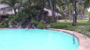 Adam şelale için merdivenlerden açık yüzme havuzunda yüzüyor