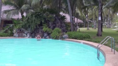 Kadın merdivenlere şelale açık yüzme havuzunda yüzüyor