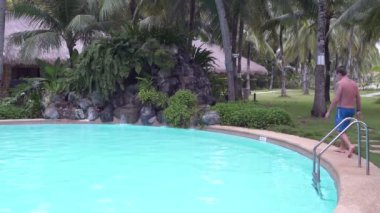 Açık havuzun kenarında bir adam oturuyor