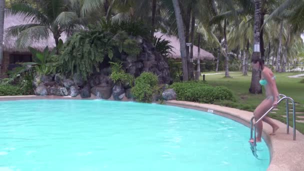 Bir kadın açık bir yüzme havuzu ve bir sürüklenir şelaleye iner — Stok video
