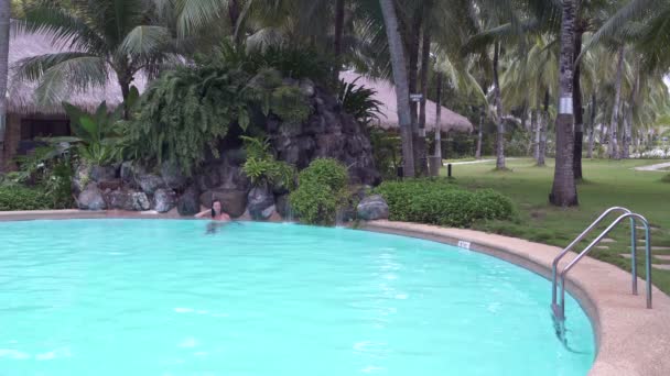 Frau fährt unter dem Wasserfall im Freibad — Stockvideo