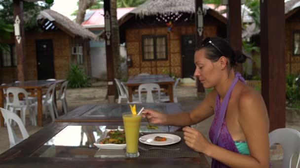 Frau sitzt in Restaurant am Tisch und legt Essen in einen Teller — Stockvideo