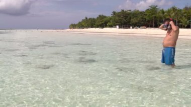 Bir adam boru ile bir maske takıyor ve denizde yüzüyor