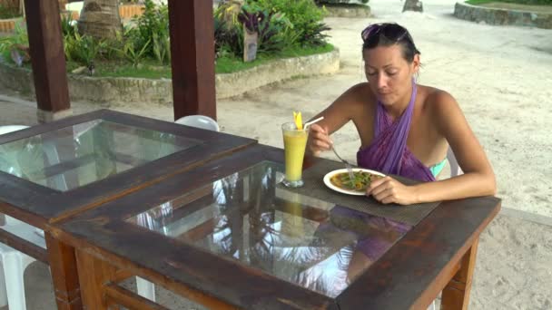 A girl sits in a restaurant on the street and eating meat with vegetables — Stock Video