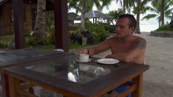 Restoran, sokak ve içecek kahve üzerinde bir masada oturan bir adam — Stok video