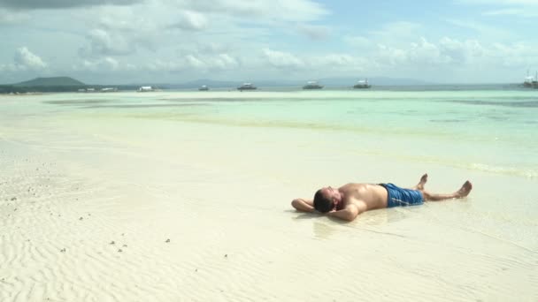 L'uomo in pantaloncini giace sulla riva del mare — Video Stock
