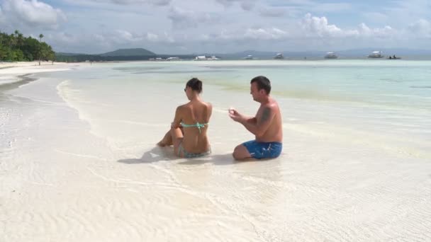 Man putting a back women sunscreen by the sea — Stock Video