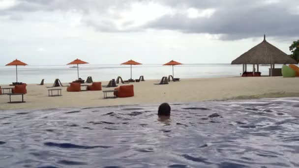 Homem nada na piscina exterior com vista para o mar — Vídeo de Stock