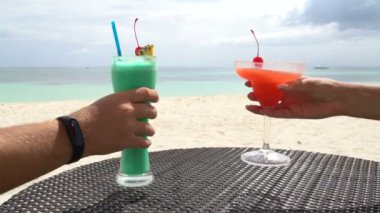 Masanın üstünde orada iki kokteyl. Erkek ve dişi eller kokteyl almak