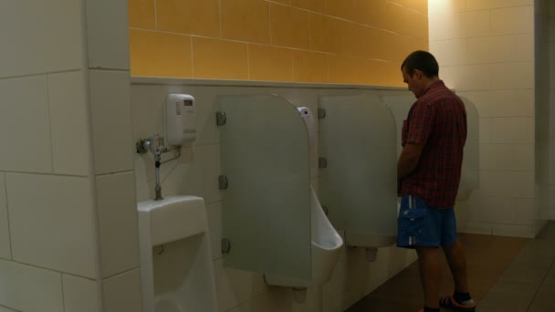Мужчина пользуется писсуаром в туалете — стоковое видео