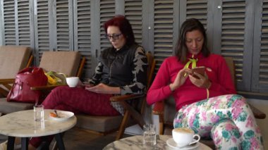 Kadınlar bir kafede kahve içme ve kullanma akıllı telefonlar