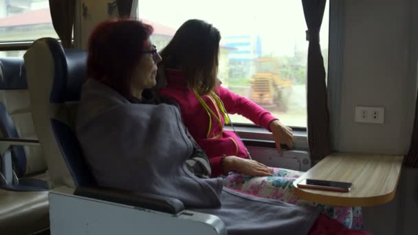電車で座っている二人の女性 女の子がアームレストから折り畳み式のテーブルを取り出す — ストック動画
