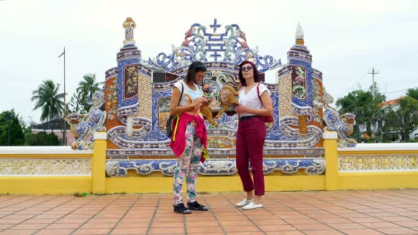 Women with smartphones are standing next to a Buddhist temple — Stock Video