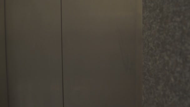Двері ліфта відчинені, і дівчина входить і хвилює її руку — стокове відео