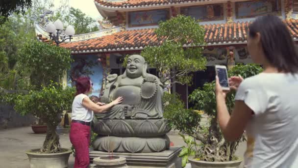 Las mujeres son fotografiadas cerca de la estatua de Buda cerca del templo — Vídeo de stock