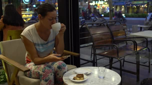 Ein Mädchen in einem Café trinkt Kaffee und isst Tiramisu — Stockvideo