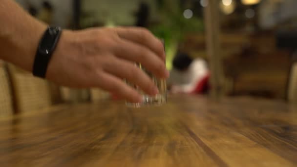 Una mano de hombre toma un vaso de agua de la mesa y la devuelve. — Vídeos de Stock