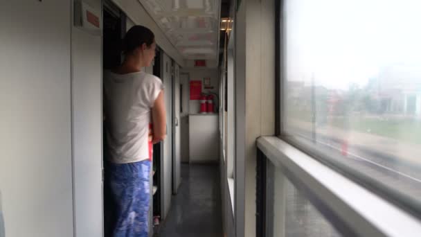Een vrouw verlaat het compartiment van de trein en gaat naar de vestibule — Stockvideo