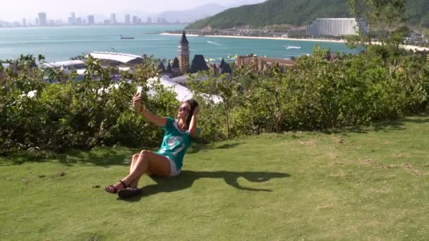 Een vrouw maakt selfie tegen de achtergrond van de zee en de bergen — Stockvideo