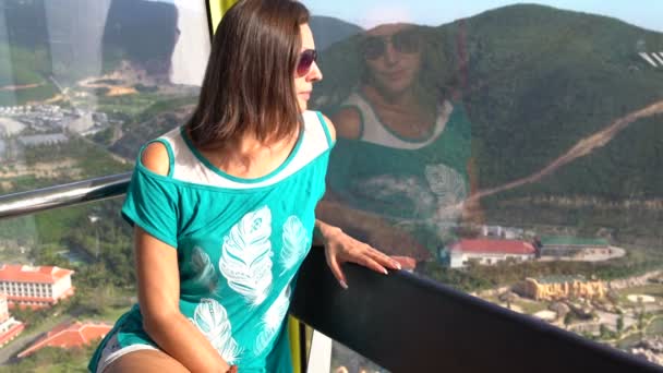 Eine Frau blickt mit einem Riesenrad auf die Landschaft — Stockvideo