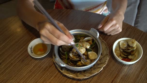 The female hand takes the mussel from the shell with chopsticks and dips it into the sauce — Stock Video