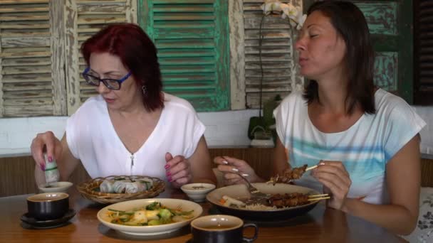 В ресторане женщины едят рисовые рулеты и куриные шашлыки — стоковое видео