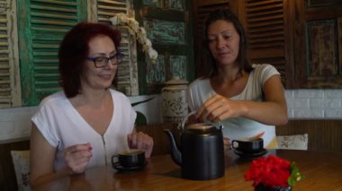 Kız bir fincan çay kazana dışarı dökülen. Kadınlar çay içmek