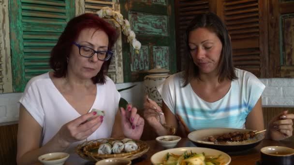 Las mujeres comen y hablan sentadas en una mesa en un restaurante vietnamita — Vídeos de Stock