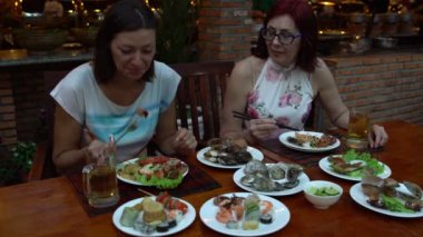 Kadınlar restoranda yemek deniz ürünleri ve konuşmak için bir masada oturmak